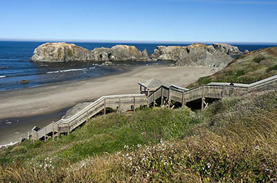 OR: South Coast Region, Coos County, Bandon Area, South Beaches, Coquille Point, Stairs lead down a grassy cliff to a sand beach spotted with large hoodoos including Arch Rock, a natural bridge [Ask for #274.350.]