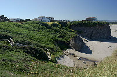 OR: South Coast Region, Coos County, Bandon Area, South Beaches, Face Rock State Wayside, House sits atop sheer rock cliffs with a wide sandy beach below, spotted with large hoodoos, and steps down the cliffs to the beach [Ask for #274.354.]