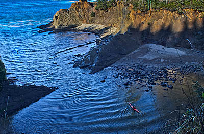 OR: Coos County, Coos Bay Area, Cape Arago Parks, Norton Gulch Viewpoint, Sea kayaker enters an isolated cove. [Ask for #276.367.]