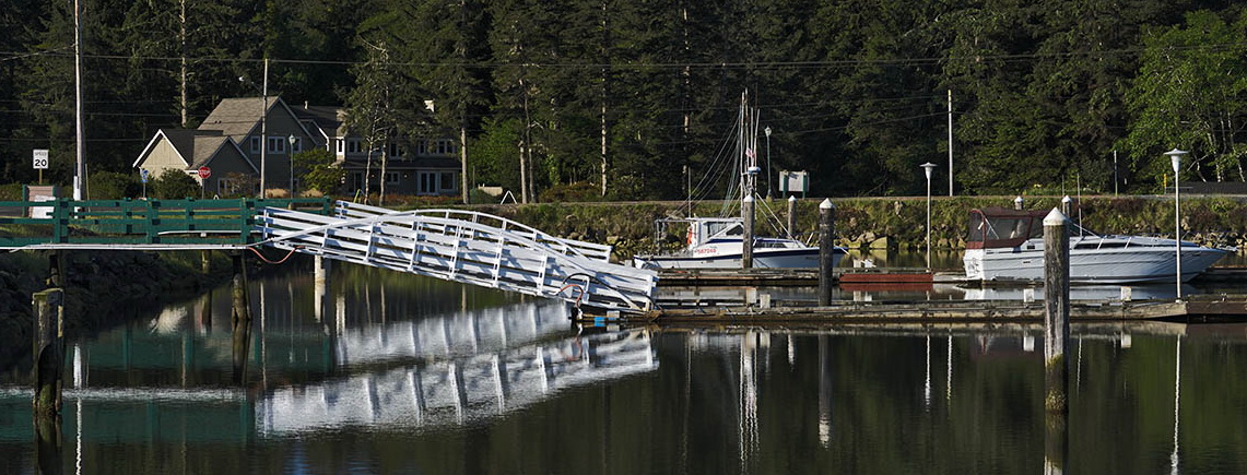 OR: South Coast Region, Douglas County, Pacific Coast, Reedsport Area, Winchester Bay, Wood bridges lead to floating docks, reflections on bay's surface. [Ask for #276.702.]